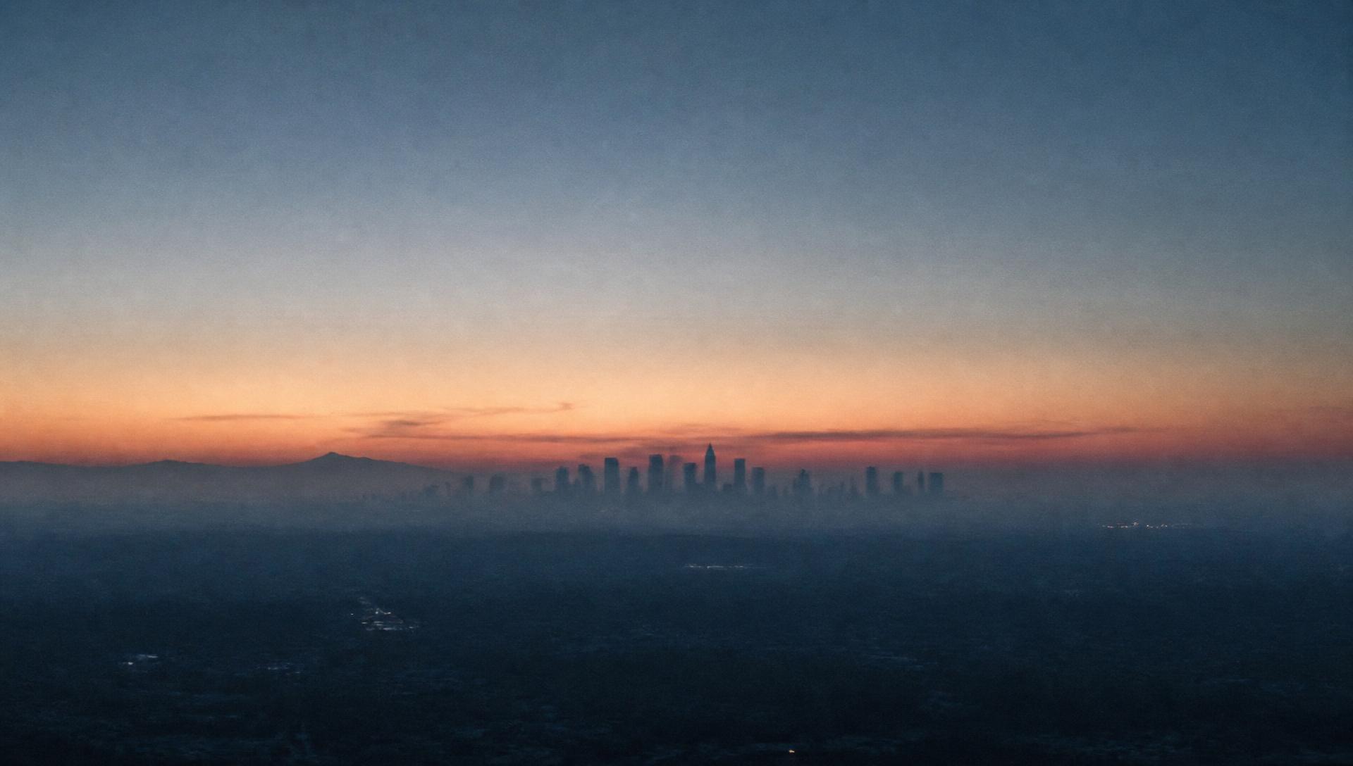 Distant city skyline at dawn under layered haze
